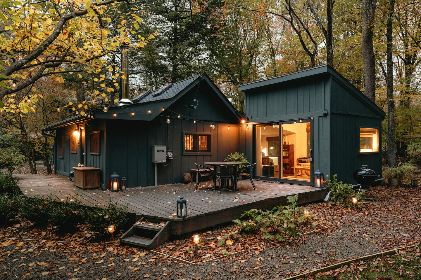 Cozy green cabin with deck in a fall forest.