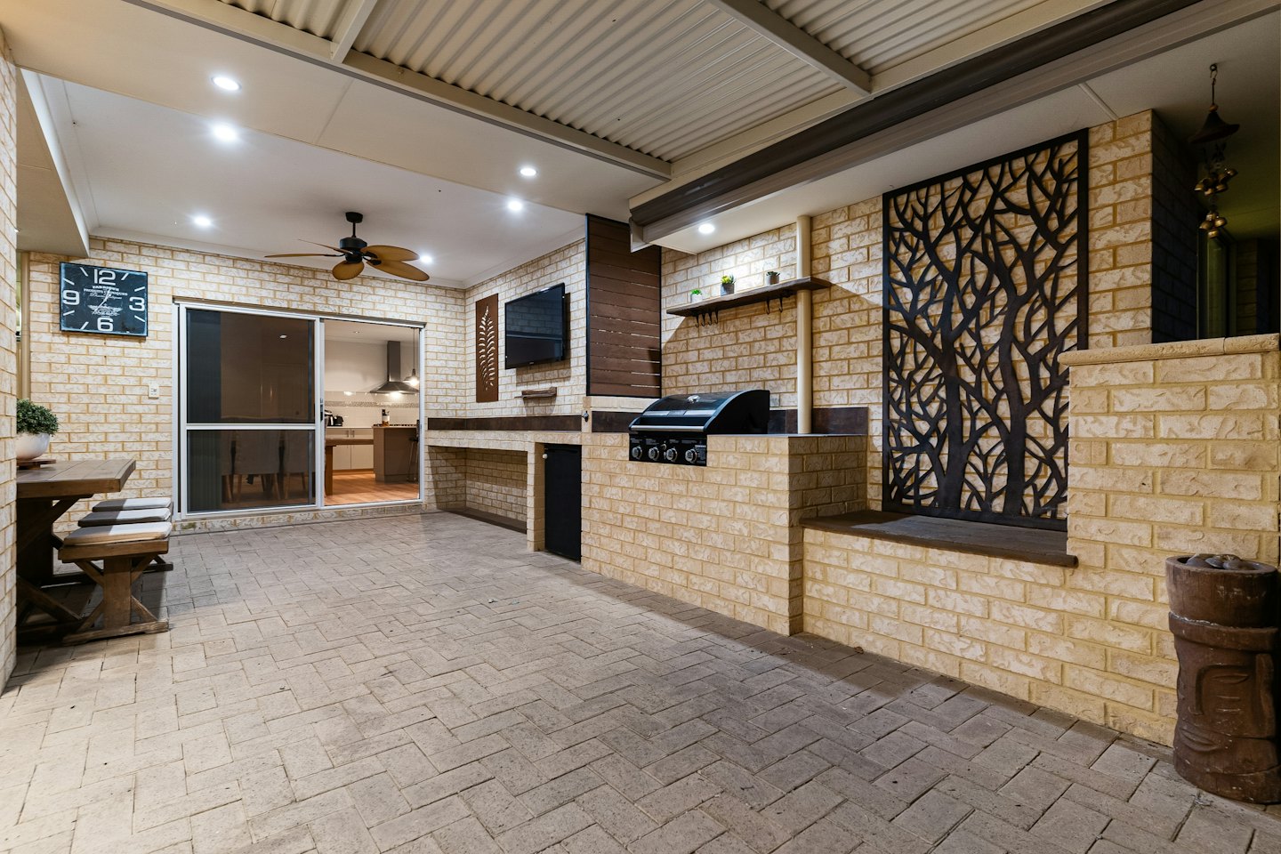 Outdoor patio kitchen with dining area and metal tree screen.
